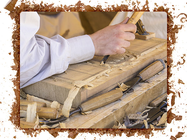 A image of a carver carving a design into wood.